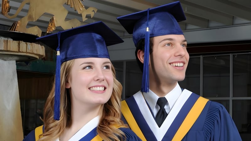 Zwei Graduierte in blauen Talaren stehen im Schulgebäude der Laurier MacDonald High School.