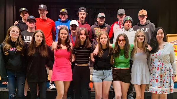 Eine Gruppe von Schülerinnen und Schülern steht gemeinsam auf einer Bühne auf dem Campus der Laval High School.