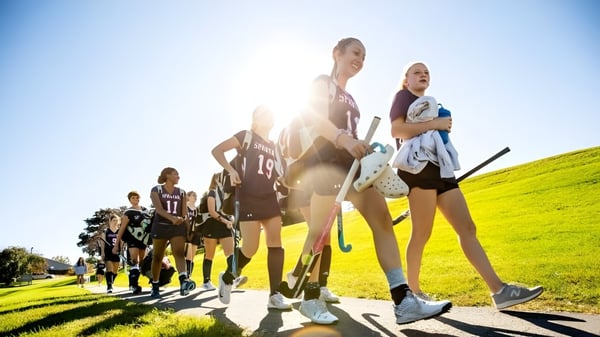 Eine Gruppe von Schülerinnen und Schülern der Lawrence Academy geht gemeinsam auf einer grünen Wiese spazieren.