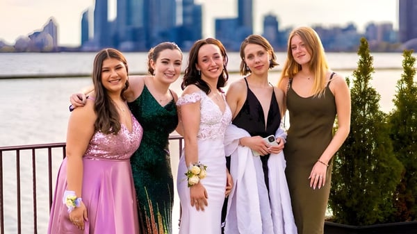 Eine Gruppe von fünf Schülerinnen der Lawrence Academy posiert vor einer Stadtsilhouette mit hohen Gebäuden.