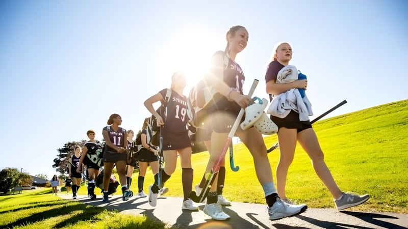 Eine Gruppe von Schülerinnen und Schülern der Lawrence Academy geht gemeinsam über eine Wiese bei sonnigem Wetter.
