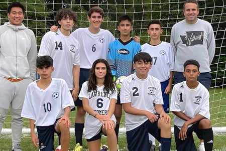 Eine Gruppe von Schülerinnen und Schülern der Lawrence Woodmere Academy posiert gemeinsam auf dem Fußballfeld vor dem Tor.