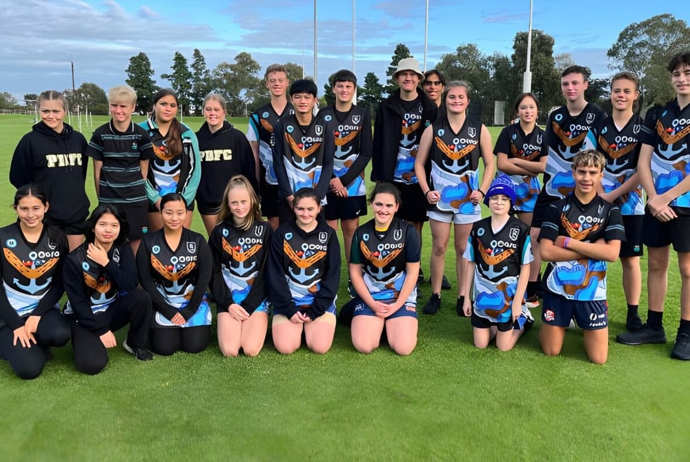 Eine Gruppe junger Athletinnen der Le Fevre High School posiert auf einem Rasenfeld vor Bäumen und blauem Himmel.