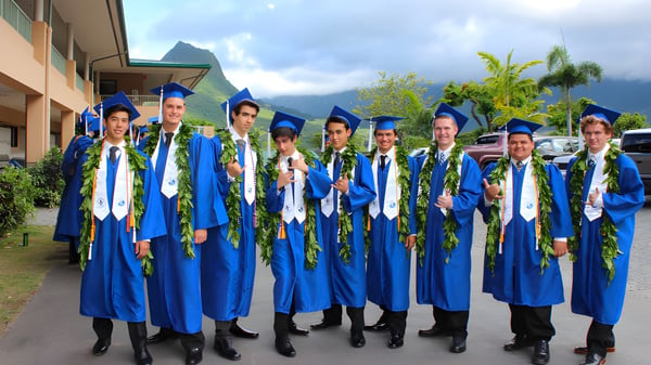 Eine Gruppe von Absolventen der Le Jardin Academy steht im Freien vor einer tropischen Landschaft.