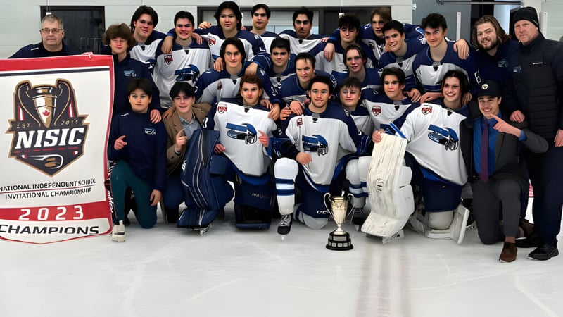 Die Hockeymannschaft der École secondaire publique Le Sommet posiert mit Pokal und Banner nach dem Gewinn der Meisterschaft.