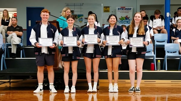 Eine Gruppe junger Schülerinnen der Leeming Senior High School steht mit Urkunden in einer Sporthalle.
