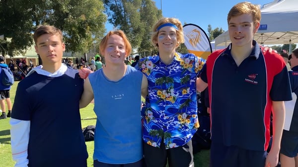 Vier Schülerinnen und Schüler der Leeming Senior High School stehen gemeinsam auf einem grasbewachsenen Feld unter blauem Himmel.