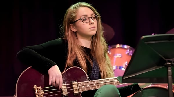 Eine Schülerin der Leighton Park School spielt auf einer Bühne eine E-Gitarre vor musikalischem Equipment.