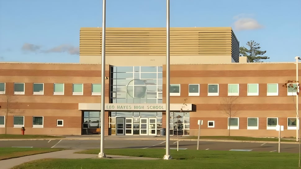 Das Gebäude der Leo Hayes High School zeigt eine moderne Fassade aus Backstein und Holz mit großen Fenstern und einem Eingang.