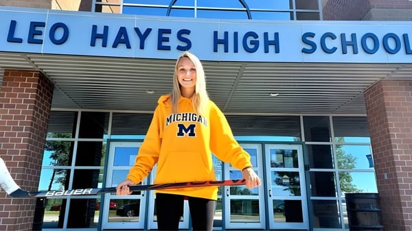 Eine Schülerin mit gelbem Michigan Sweatshirt steht vor dem Eingang der Leo Hayes High School.