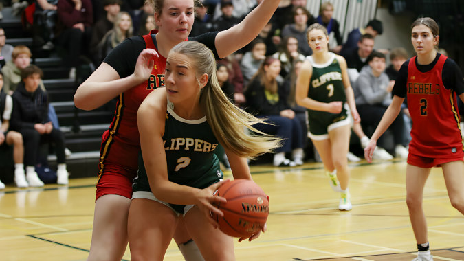 Eine Basketballspielerin in rotem Trikot dribbelt den Ball auf dem Spielfeld der Lethbridge Collegiate Institute.