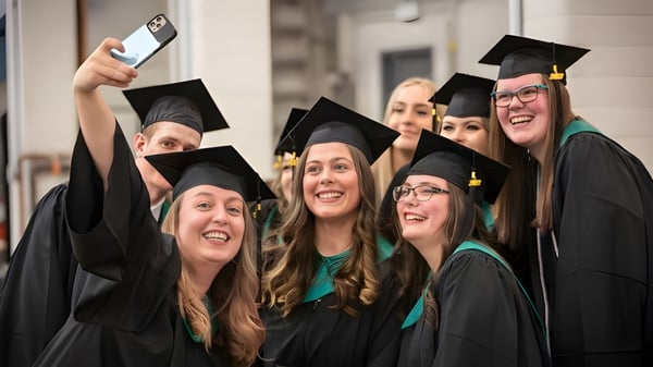 Eine Gruppe von Absolventinnen und Absolventen des Lethbridge Collegiate Institute posiert in Abschlusskleidung vor einem Hochschulgebäude.