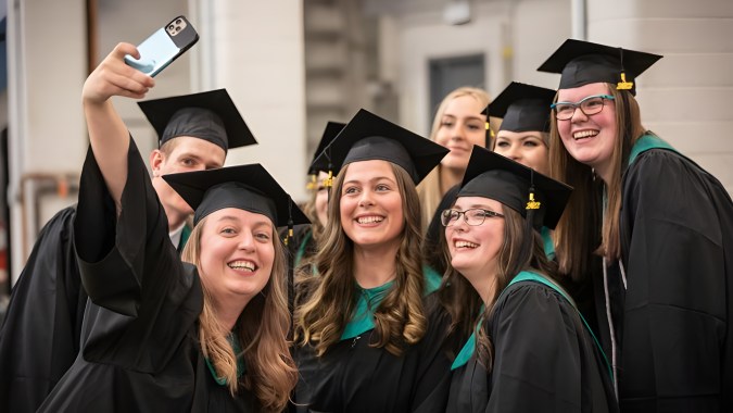 Eine Gruppe von Absolventinnen und Absolventen des Lethbridge Collegiate Institute macht vor einem Gebäude ein Selfie in ihren Abschlussroben.