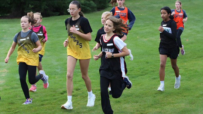 Eine Gruppe junger Sportlerinnen läuft gemeinsam auf einem Feld auf dem Campus der Lethbridge School Division.