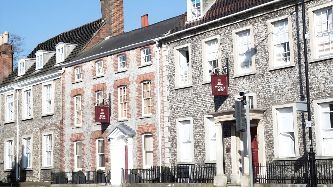 Eine Reihe alter Backsteingebäude mit aufwendiger Architektur auf dem Gelände der Lewes Old Grammar School vor klarem blauen Himmel.