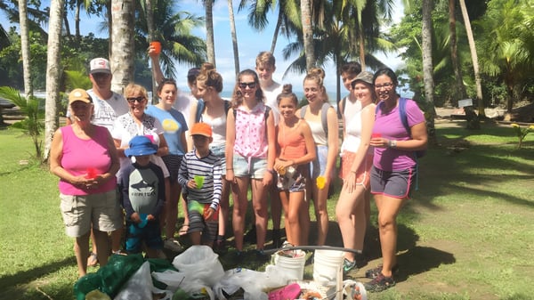 Eine Gruppe von Menschen steht vor tropischer Vegetation auf dem Gelände der Lewes Old Grammar School.