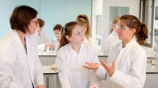 Schülerinnen der Lewes Old Grammar School diskutieren im weißen Kittel in einem Laborraum.