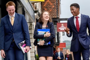 Drei Personen in professioneller Kleidung gehen gemeinsam eine Straße entlang auf dem Gelände der Lewes Old Grammar School.