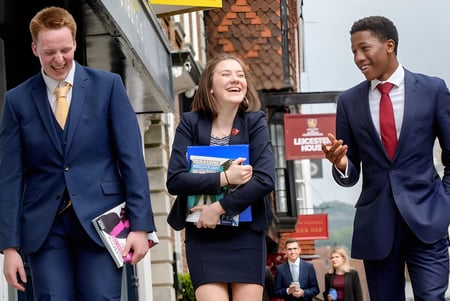 Drei Personen in professioneller Kleidung gehen gemeinsam eine Straße entlang auf dem Gelände der Lewes Old Grammar School.