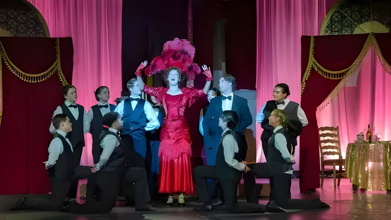 Schüler der Liberty Christian Academy stehen in formeller Kleidung und einem roten Kostüm auf einer Bühne mit dekorativen Vorhängen.