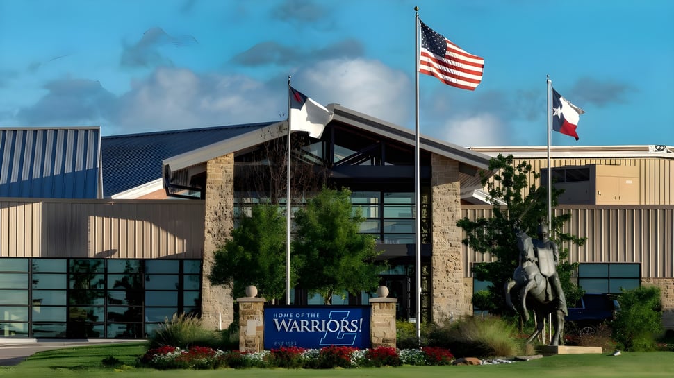 Das moderne Gebäude der Liberty Christian Academy mit der amerikanischen und texanischen Flagge vor grüner Umgebung.