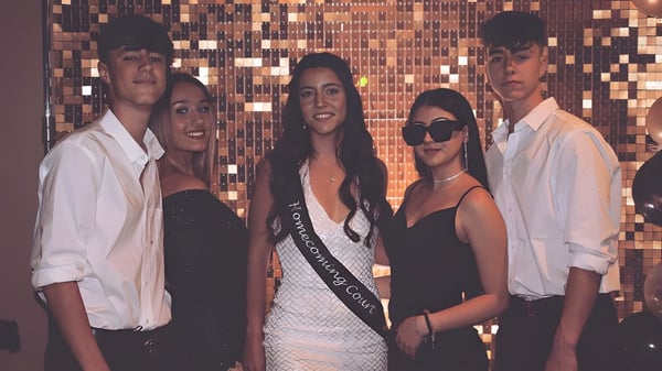 Eine Gruppe Schüler der Life Prep Academy posiert in formeller Kleidung vor einem metallischen Hintergrund bei einer Feier.