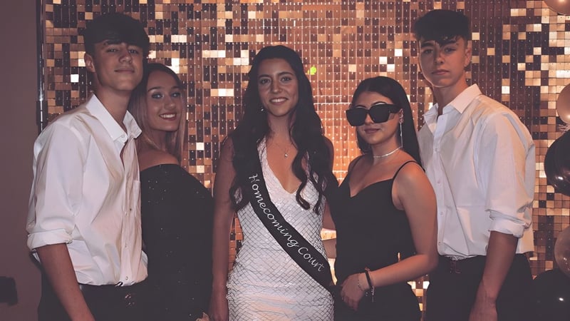 Eine Gruppe von Schülerinnen und Schülern der Life Prep Academy steht vor einem metallischen Hintergrund in formeller und legerer Kleidung.