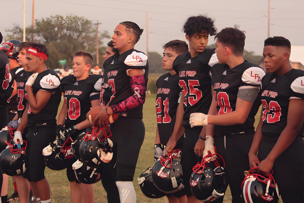 Eine Gruppe von jungen Athleten steht gemeinsam auf dem Sportfeld der Life Prep Academy.
