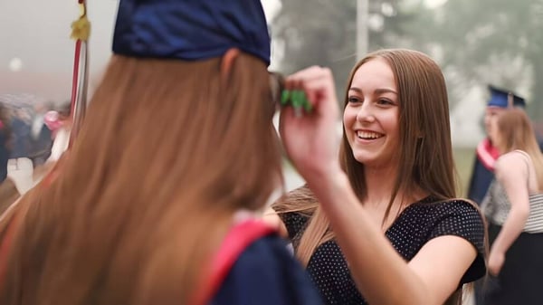 Eine Schülerin der Lillian Osborne High School unterhält sich lachend mit einer weiteren Person im belebten Außenbereich der Schule.
