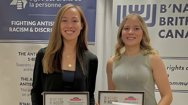 Zwei lächelnde Frauen stehen vor Bannern der Anti-Rassismus-Organisation auf dem Gelände der Lillian Osborne High School.