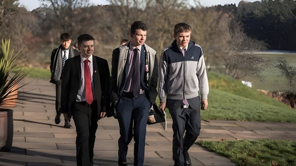 Vier Schüler der Lime House School gehen auf einem von Bäumen umgebenen Weg.