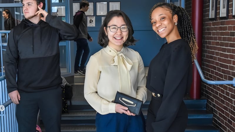 Drei Personen stehen auf einer Treppe vor einem Backsteingebäude auf dem Campus der Lincoln Academy.