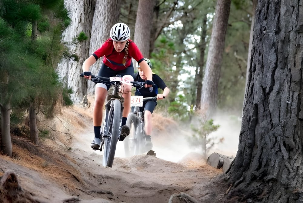 Ein Schüler der Lincoln High School fährt mit einem roten Trikot Fahrrad auf einem Waldweg.