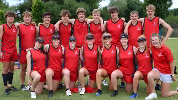 Eine Gruppe Schüler der Lincoln High School in roten Sportuniformen posiert gemeinsam im Freien vor einer grünen Landschaft.