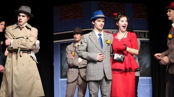 Eine Gruppe Schüler in Vintage-Kleidung steht vor einem Backsteingebäude auf dem Campus der Lincoln High School.