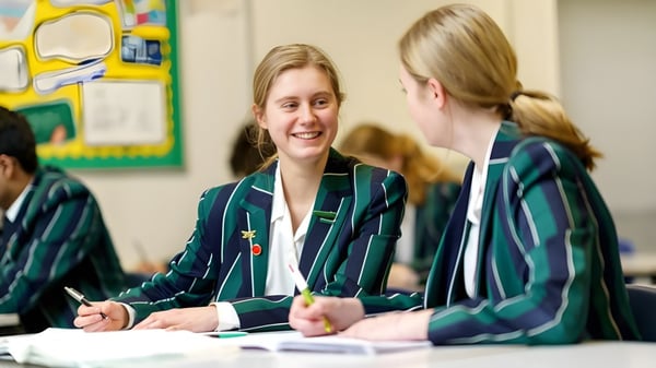 Zwei Schülerinnen der Lincoln Minster School führen in einem farbenfrohen Klassenzimmer ein Gespräch.