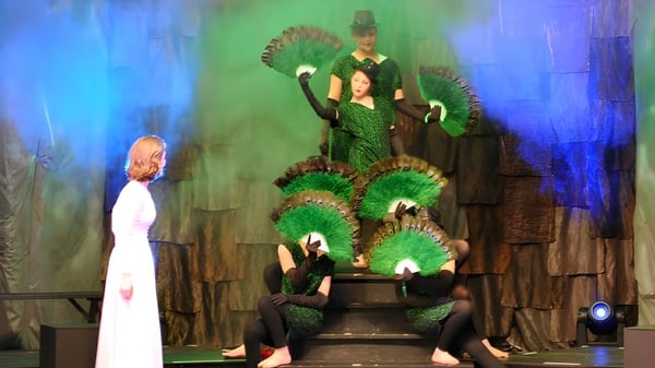 Schüler der Linden Hall führen ein Theaterstück mit farbenfrohen Kostümen auf einer fantasievollen Bühne auf.