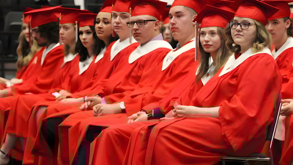 Eine Gruppe von Absolventinnen und Absolventen der Lindsay Thurber Comprehensive High School sitzt in roten Talaren bei der Abschlussfeier.