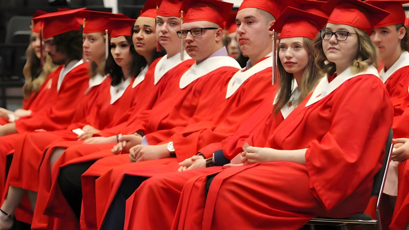 Eine Gruppe von Absolventinnen und Absolventen der Lindsay Thurber Comprehensive High School sitzt in roten Talaren bei der Abschlussfeier.