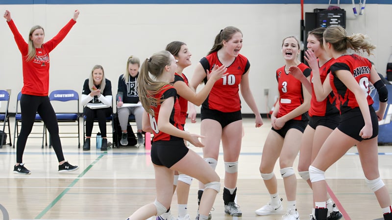 Schülerinnen der Lindsay Thurber Comprehensive High School feiern zusammen auf dem Volleyballfeld während eines Spiels.
