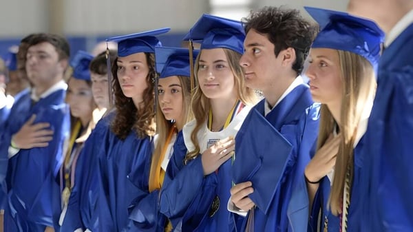 Absolventinnen und Absolventen des Lisgar Collegiate Institute in blauen Abschlussroben stehen gemeinsam vor einem blau-weißen Hintergrund.