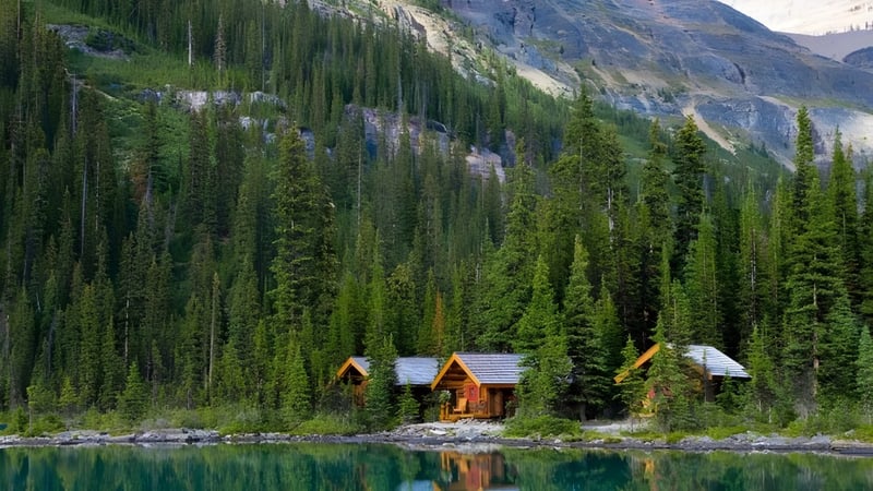 Eine ruhige Berglandschaft mit See und Hütten, umgeben von Wäldern, ohne direkten Bezug zum Lisgar Collegiate Institute.