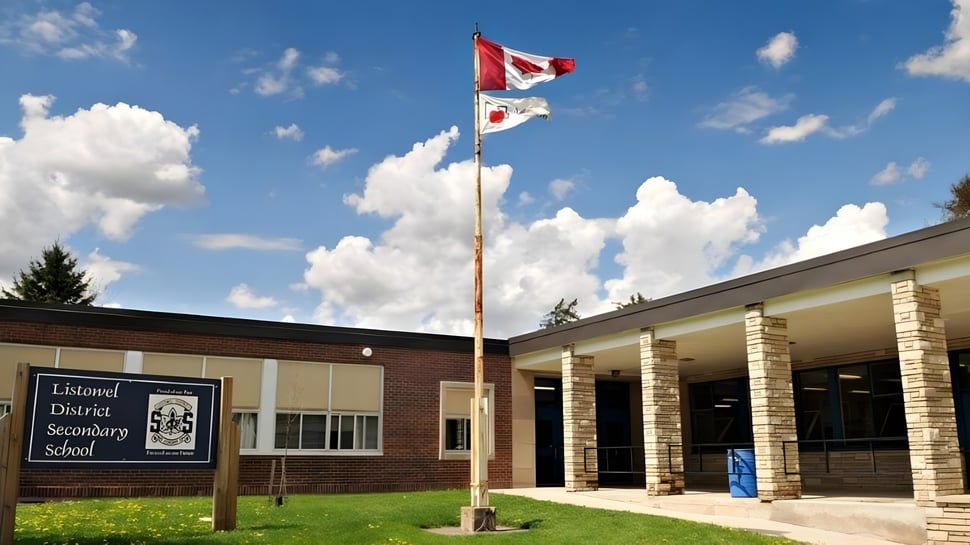 Die kanadische Flagge weht auf dem Dach des Backsteingebäudes der Listowel District Secondary School vor einem bewölkten Himmel.