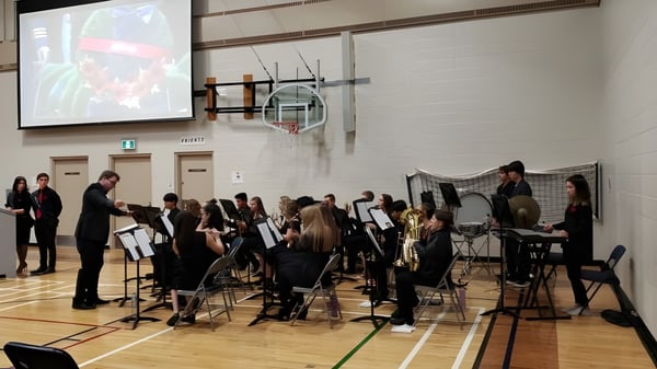 Schüler des Livingstone School spielen in einem Orchester auf der Bühne einer Sporthalle.