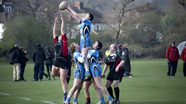 Eine Gruppe von Schülerinnen und Schülern spielt Rugby auf dem Spielfeld des Llandovery College während Zuschauer im Hintergrund zuschauen.