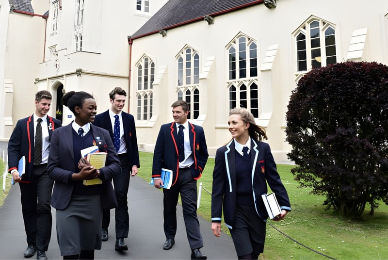Eine Gruppe von Schülerinnen und Schülern in Schuluniformen läuft auf dem Gelände des historischen Gebäudes des Llandovery College.