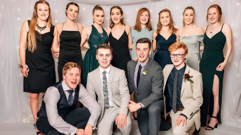 Eine Gruppe von Schülerinnen und Schülern der Logan Park High School posiert gemeinsam vor einem weißen Hintergrund in formaler Kleidung.