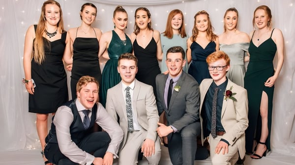 Eine Gruppe von Schülerinnen und Schülern der Logan Park High School posiert gemeinsam vor einem weißen Hintergrund in formaler Kleidung.