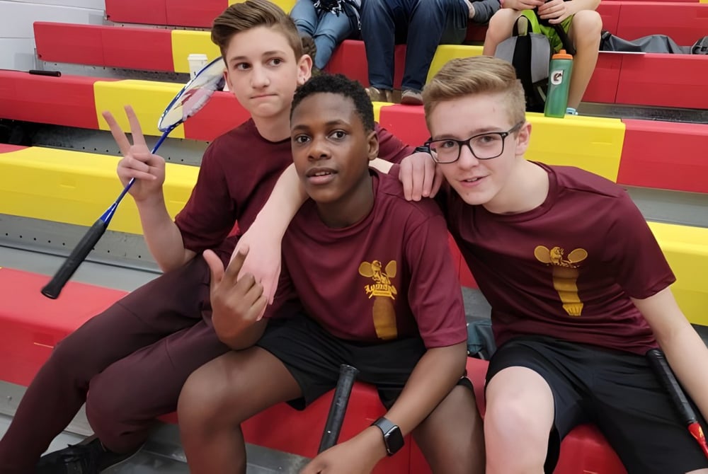 Drei Schülerinnen und Schüler der Lomond Community School posieren gemeinsam in der Sporthalle mit bunten Matten im Hintergrund.