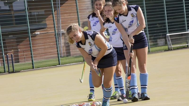 Eine Gruppe junger Athletinnen steht im Sportfeld vor einem Backsteingebäude auf dem Campus der Lomond School.
